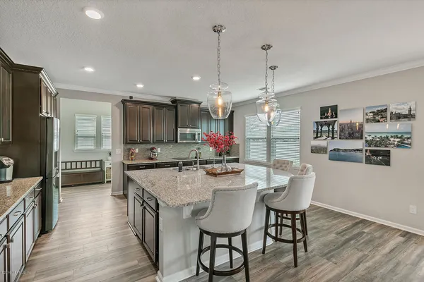 a kitchen with kitchen island a dining table chairs stainless steel appliances and cabinets