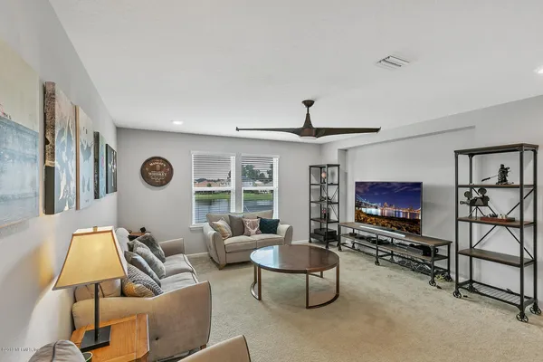 a living room with furniture a flat screen tv and a large window