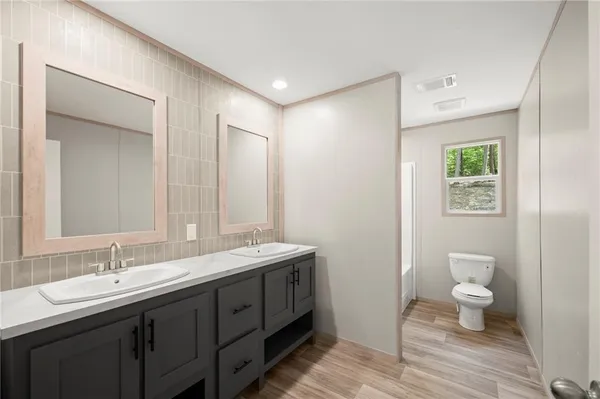 a bathroom with a double vanity sink a toilet and a mirror