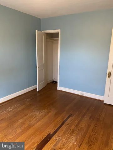 a view of an empty room with wooden floor and closet