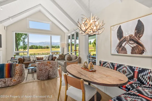 a view of a dining room with furniture a chandelier and large windows
