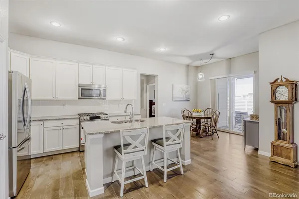 a kitchen with stainless steel appliances a table chairs refrigerator and cabinets