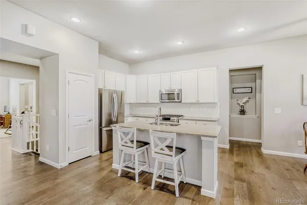 a kitchen with stainless steel appliances a white table chairs and a refrigerator
