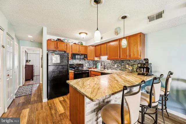 a kitchen with stainless steel appliances kitchen island granite countertop a refrigerator a oven a sink with a dining table and chairs