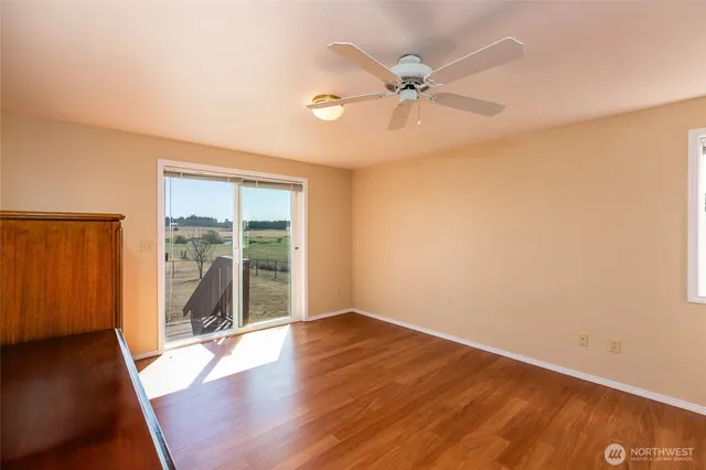 an empty room with wooden floor fan and windows