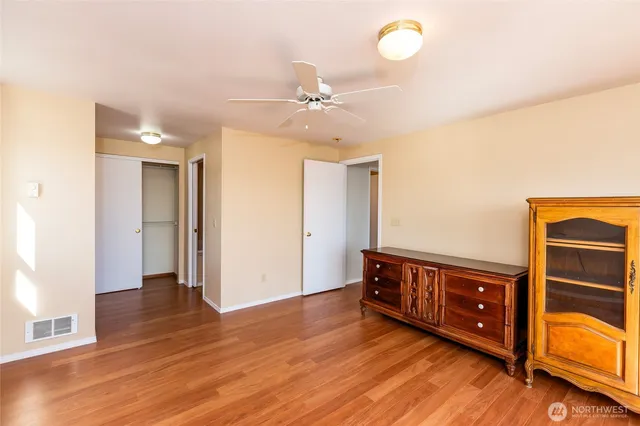 a view of an empty room with window and wooden floor