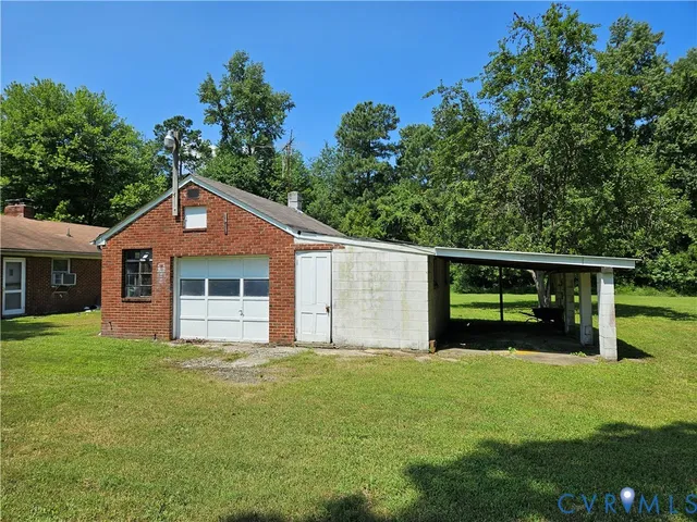 a house that is sitting in the grass with tress in the background