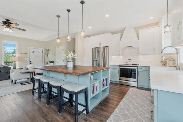 a kitchen with stainless steel appliances a table chairs stove and kitchen island