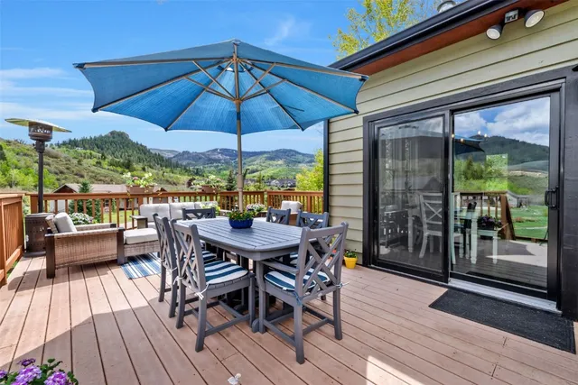 a view of a roof deck with table and chairs under an umbrella with wooden floor