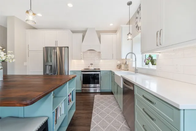 a kitchen with stainless steel appliances granite countertop a sink a stove and a refrigerator