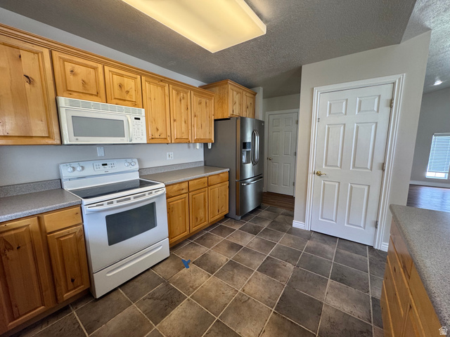 88 Canterbury Lane Logan, UT 84321 - Photo 6 of 37 Kitchen featuring natural wood-finish cabinetry, solid surface countertops, and durable tile flooring
