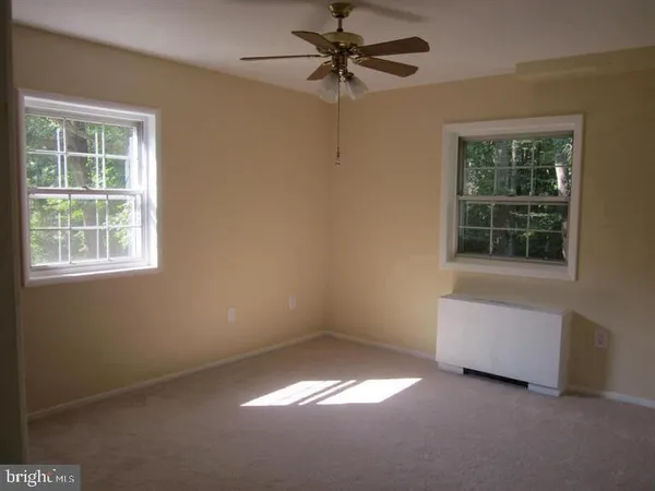 an empty room with windows and fan