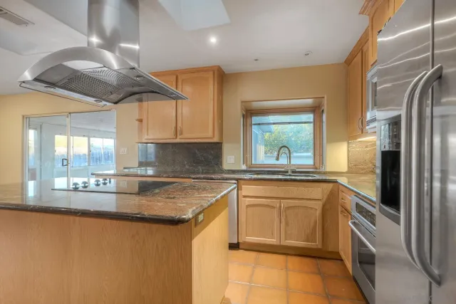 a kitchen with stainless steel appliances granite countertop a sink a stove and a refrigerator
