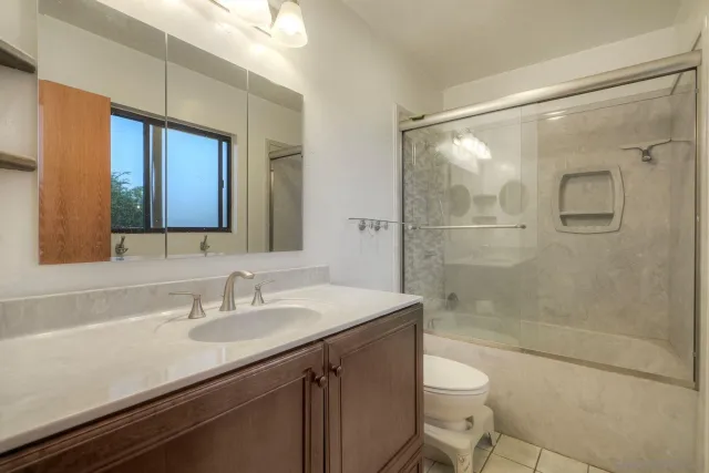 a bathroom with a sink a toilet a mirror and shower