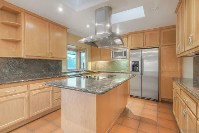 a kitchen with kitchen island granite countertop a sink a counter top space appliances and cabinets