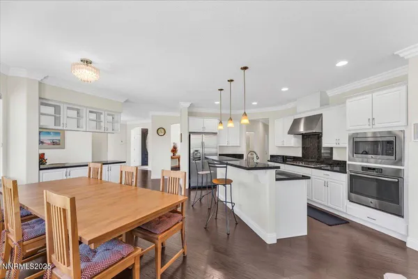a kitchen with stainless steel appliances granite countertop a stove and a view of living room