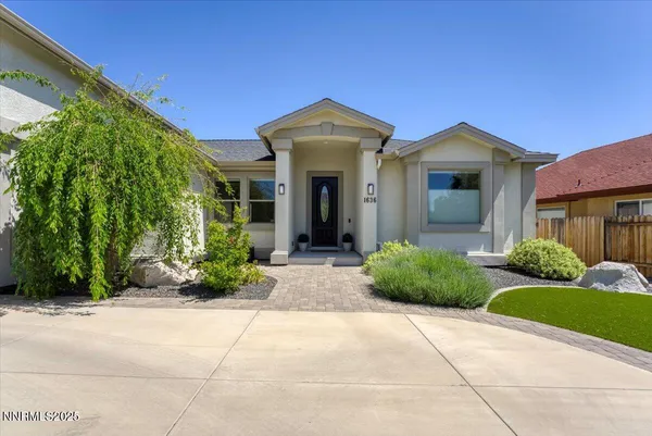 a view of a brick house with a large windows plants and large trees