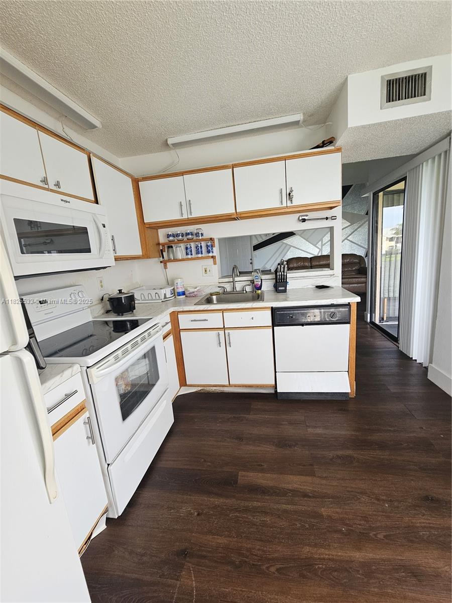 1002 Adams Avenue, Unit 1002E Homestead, FL 33034 - Photo 9 of 13 a kitchen with kitchen island granite countertop white cabinets and white appliances