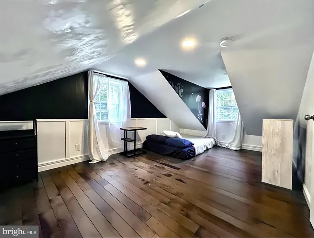 a view of an empty room with wooden floor and stairs