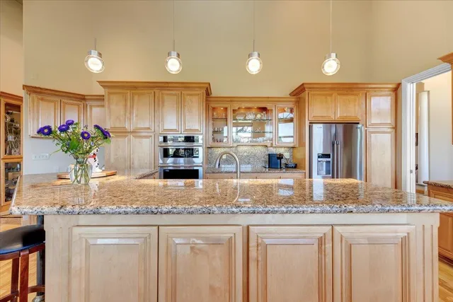a kitchen with stainless steel appliances granite countertop a stove a refrigerator a kitchen island a dining table and chairs with wooden floor