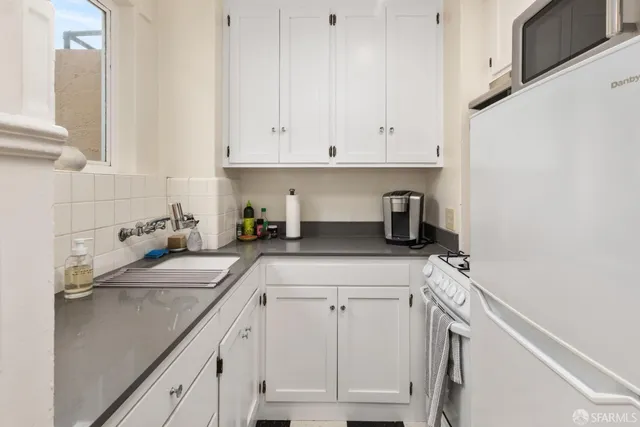 a kitchen with white cabinets and appliances