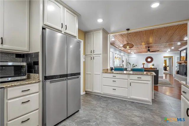 a kitchen with cabinets stainless steel appliances and wooden floor