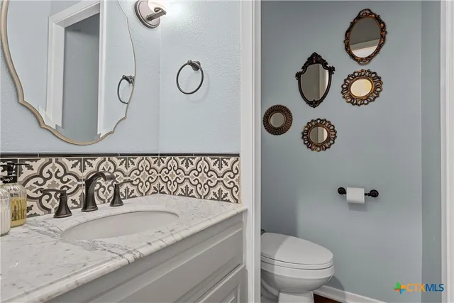a bathroom with a granite countertop sink and a toilet