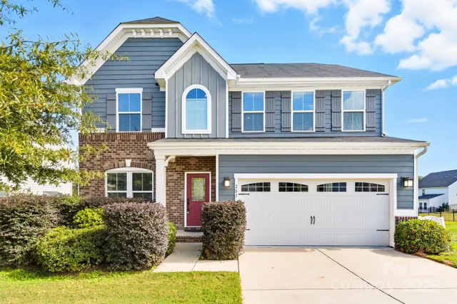 a view of a white house with large windows and a small yard