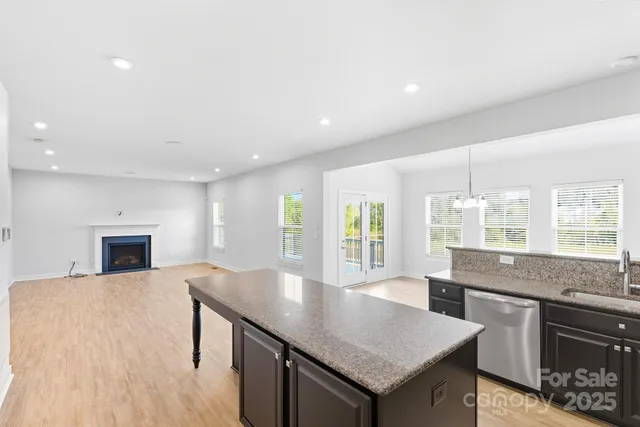 a kitchen with granite countertop a stove a sink a refrigerator and blue cabinets with wooden floor