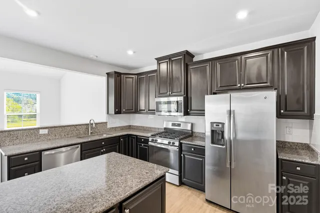 a kitchen with stainless steel appliances granite countertop a sink stove and refrigerator