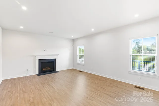 an empty room with wooden floor a fireplace and windows