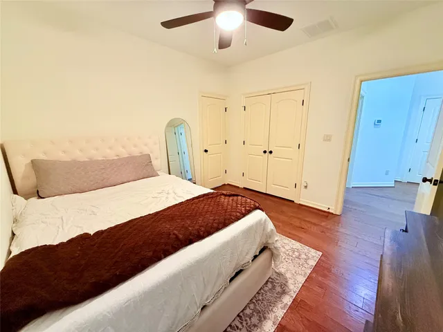 a spacious bedroom with a bed and wooden floor