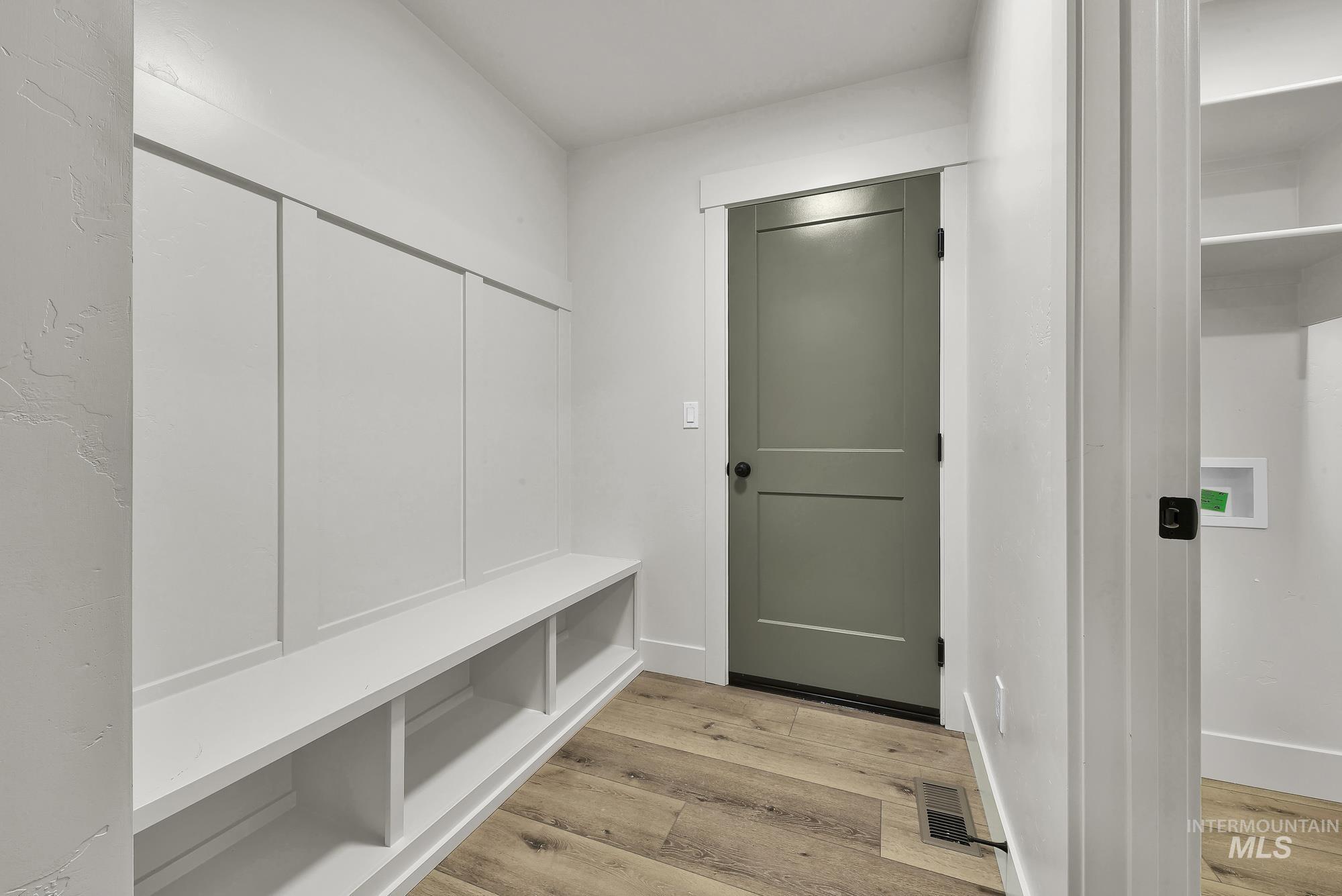 1130 Velvet Loop Wilder, ID 83676 - Photo 33 of 35 Built-in white storage bench with open shelving, wood-finish flooring, and a neutral-toned door with matte black hardware