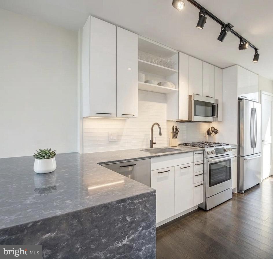 a kitchen with stainless steel appliances a stove a sink and white cabinets