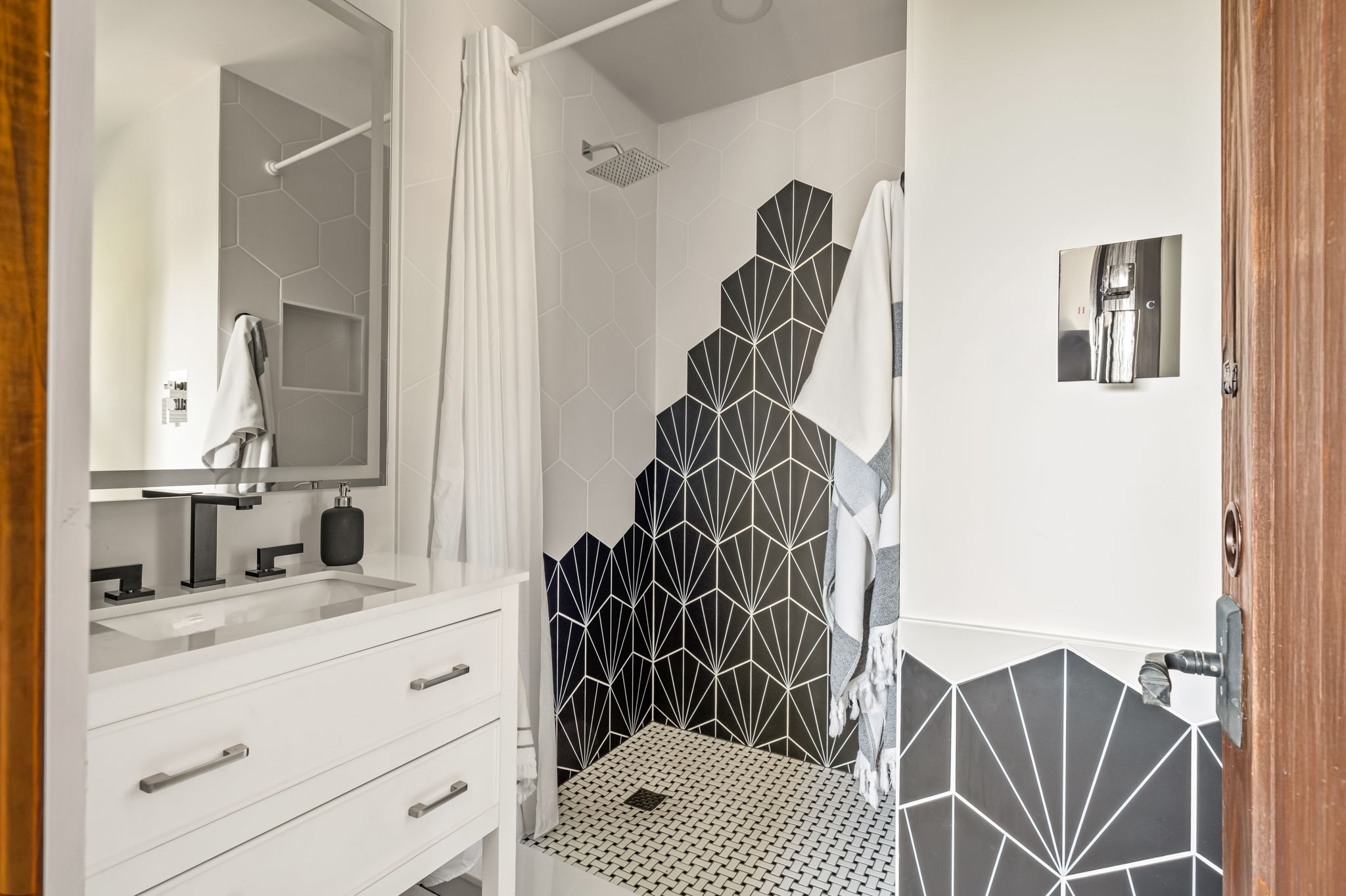 1111 West 12th Street, Unit 107 Austin, TX 78703 - Photo 31 of 38 Shower with black and white patterned tile, a contrasting white penny tile floor, and a matte black rainfall showerhead
