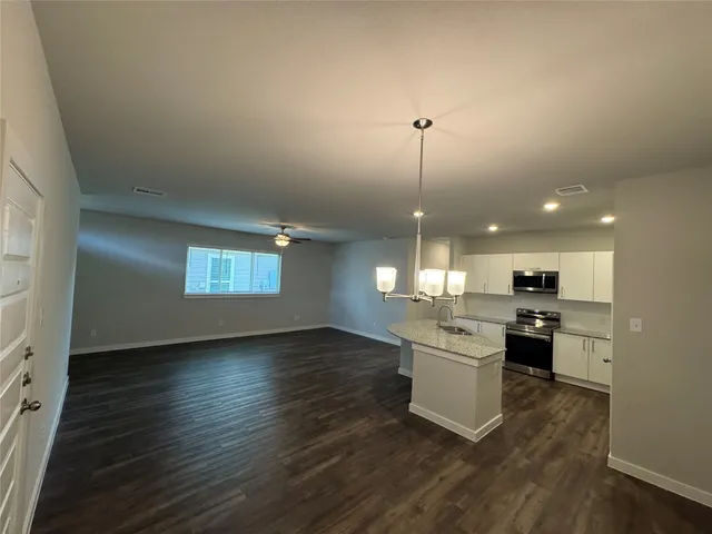 a kitchen with stainless steel appliances granite countertop a sink cabinets and wooden floor
