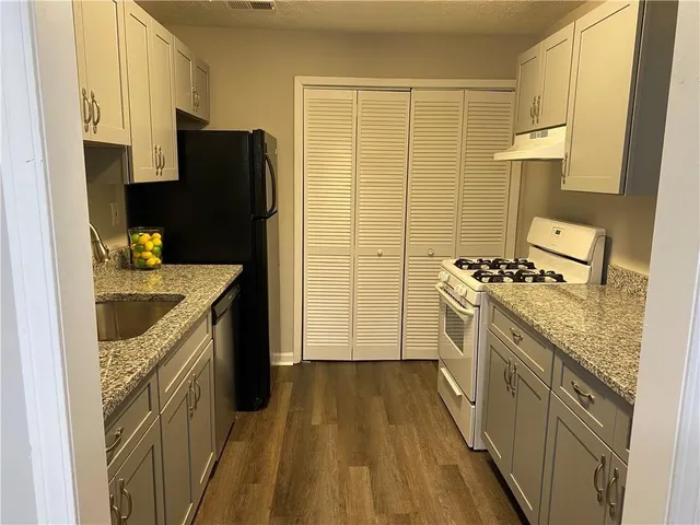 a kitchen with granite countertop a sink stove and refrigerator