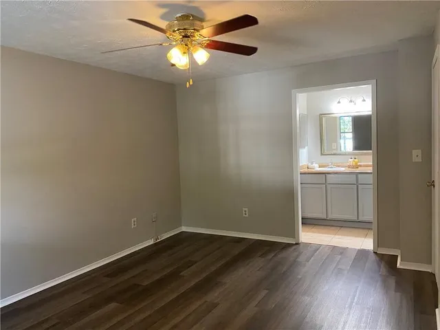 an empty room with wooden floor and a ceiling fan