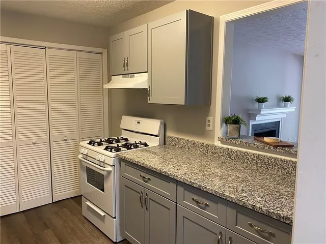 a kitchen with granite countertop white cabinets and white appliances