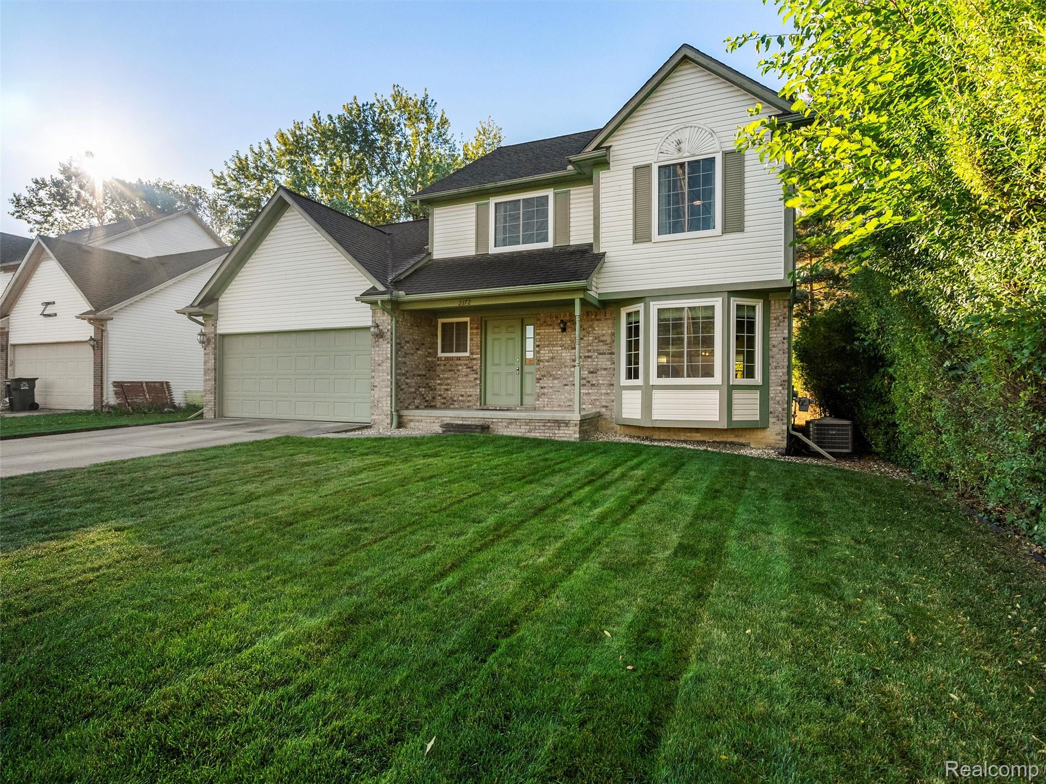 2172 Orpington Road Troy, MI 48083 - Photo 2 of 27 Traditional-style house with a front yard, brick siding, covered porch, concrete driveway, and an attached garage