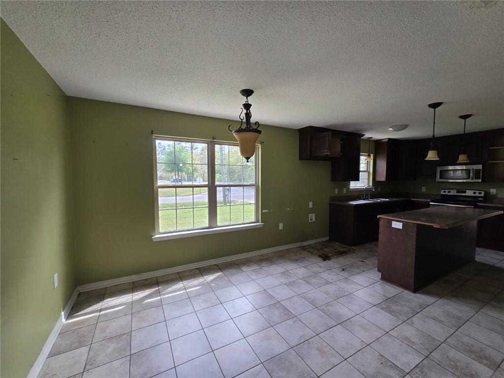 141 McRae Street Atmore, AL 36502 - Photo 18 of 25 a kitchen with granite countertop a stove a sink and a microwave