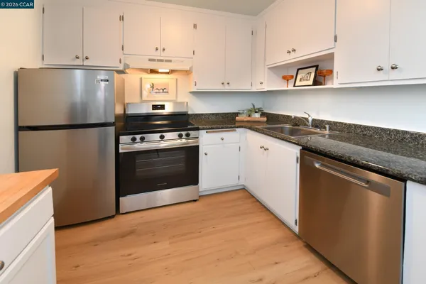 a kitchen with stainless steel appliances granite countertop a stove a refrigerator and a sink