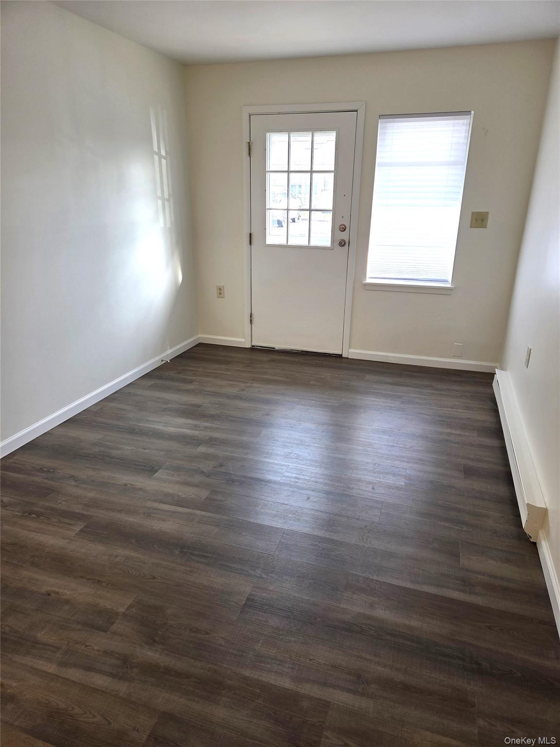 186 C Ventry Court Ridge, NY 11961 - Photo 17 of 25 an empty room with wooden floor and windows