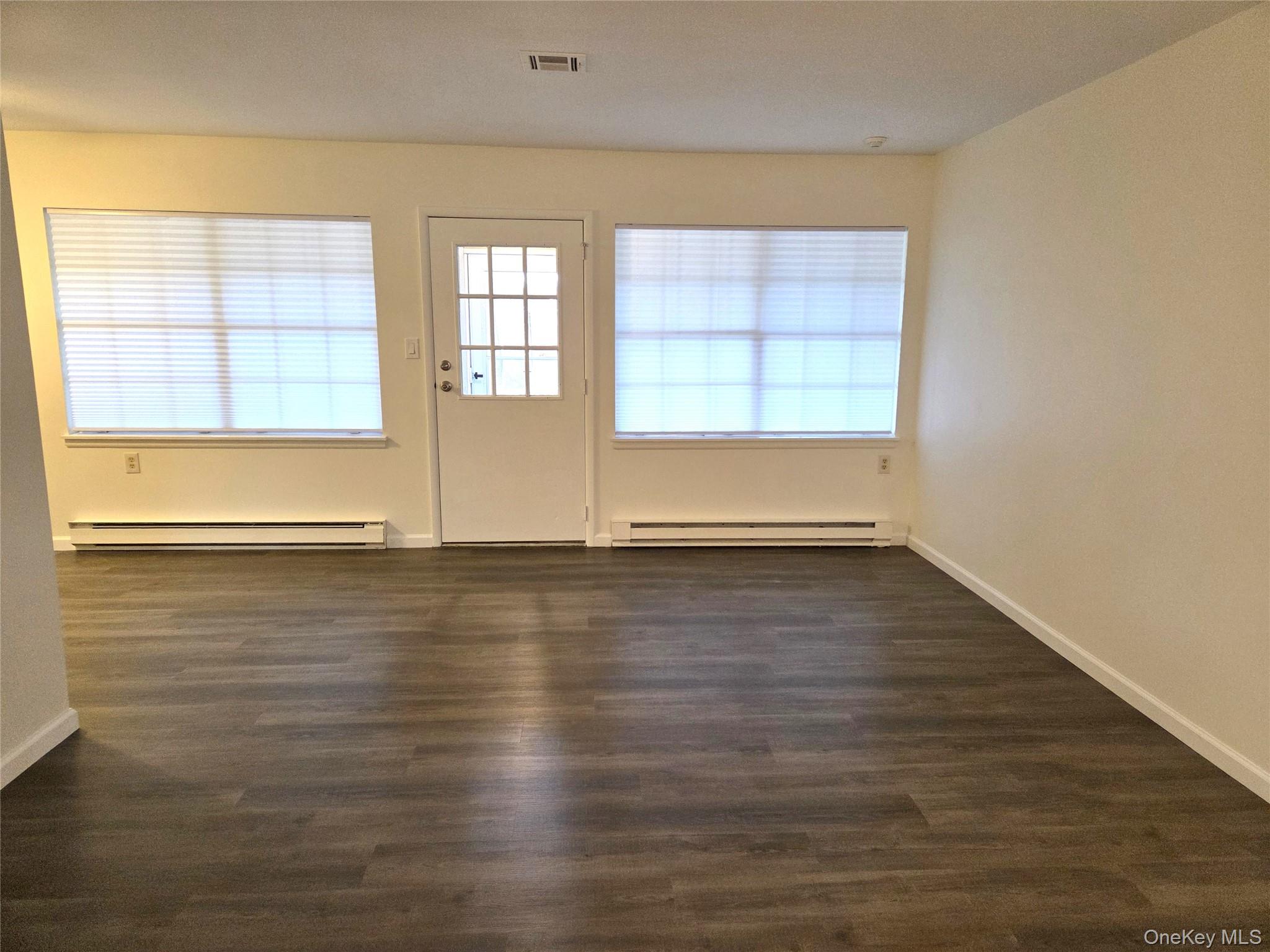 186 C Ventry Court Ridge, NY 11961 - Photo 7 of 25 an empty room with wooden floor and windows