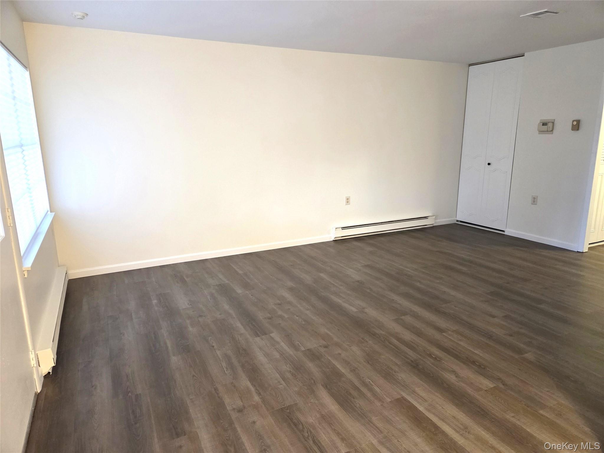 186 C Ventry Court Ridge, NY 11961 - Photo 8 of 25 an empty room with wooden floor and windows