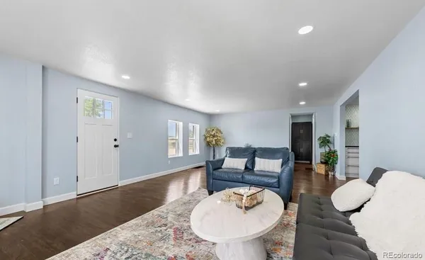a living room with furniture a dining table and kitchen view with wooden floor