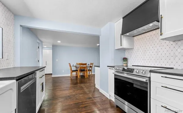 a kitchen with granite countertop a stove top oven a sink a dining table and chairs