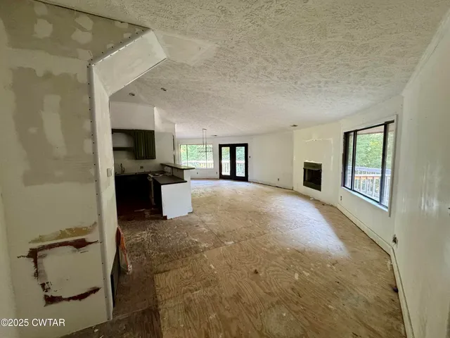 a view of an empty room with a fireplace and a window