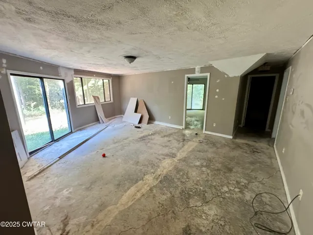 an empty room with windows and ceiling fan