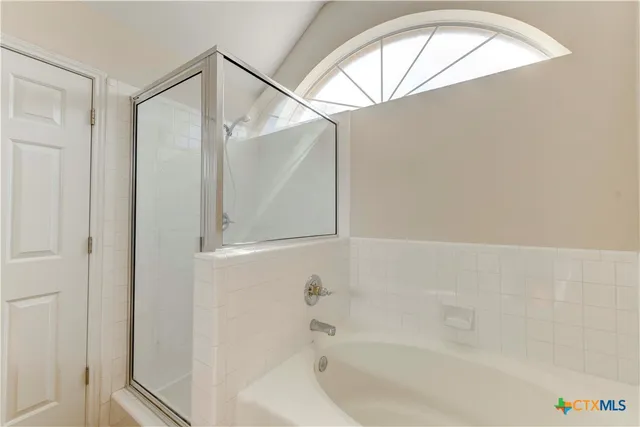 a bathroom with a bathtub a window and a shower